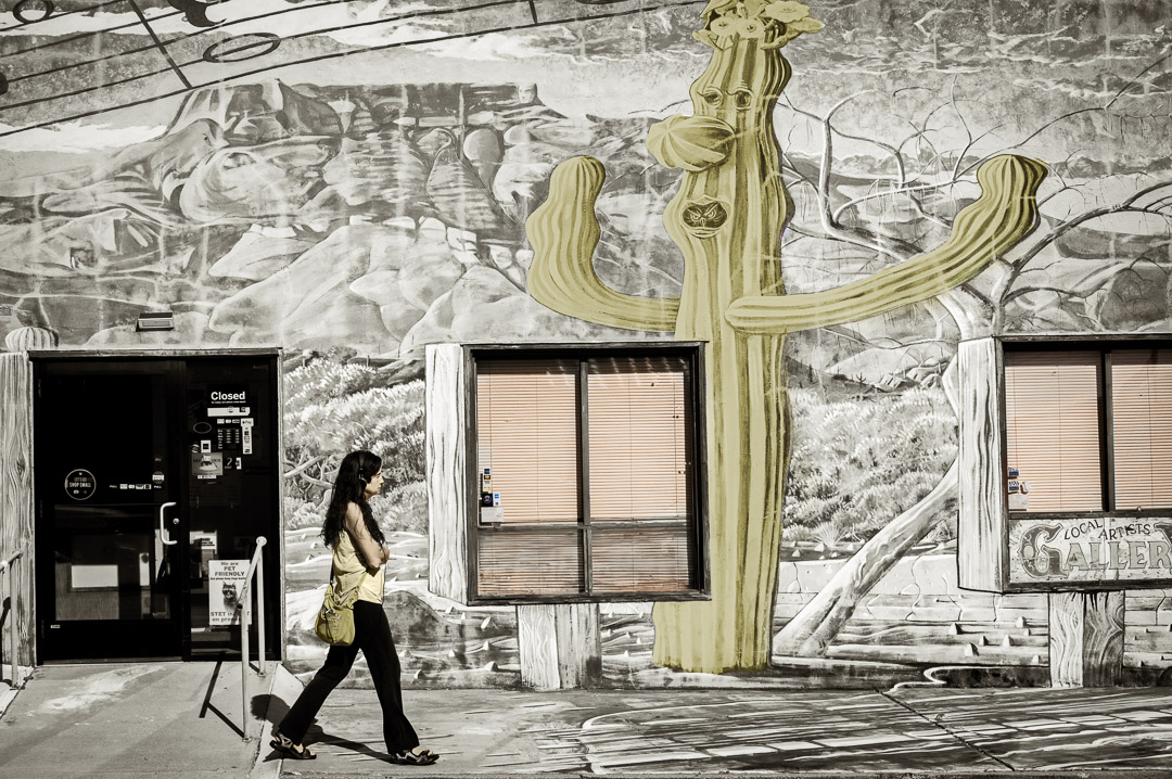 Woman walking in front of mural of desert landscape including giant cactus.